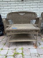 Front view of brown wicker patio loveseat with armrests, showing the full loveseat and coffee table below it.