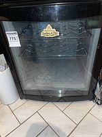 Full shot of black Heintzman Cantina di Vino wine fridge with glass door and four wire shelves inside.