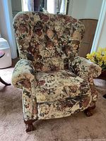 Front view showing floral tufted wing back chair and wood claw feet