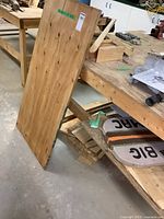 Photo showing 24x48 plywood sheet leaning against a wooden workbench with smaller wood pieces below and nearby.