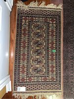 Full view of the rectangular wool rug laid flat on wood floor showing geometric patterns and edges.