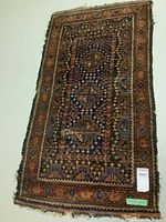Full view of rectangular traditional wool rug showing pattern, colors, and wear.