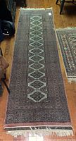 Full view of the wool runner carpet laid out on wooden flooring, showing the full length and pattern of the carpet with visible wear.