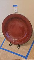 Front view of red glazed ceramic platter on stand