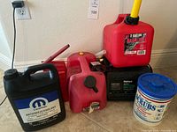 Group shot showing all items: charger, gas jug, antifreeze jug, battery tester, additional gas can, hand-cleaner towels