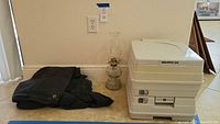 Lamp, tarp, and portable toilet side by side against wall