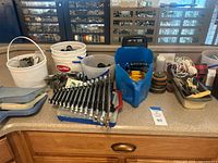 Overview of lot on countertop showing buckets, wrench set, screw kit, tape measure and hand tools