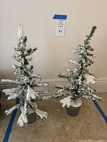 Two matching faux snow-covered tabletop trees in metal buckets