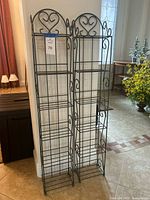 Both grey metal scrollwork shelves standing side by side showing overall design and height