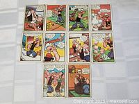 Top-down view of 10 Popeye trading cards arranged in three rows on a white surface, showing colorful comic scenes.