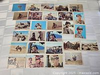 Top-down view of 35 Rat Patrol trading cards laid out on a flat white surface, showing various scenes and characters