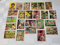 28 vintage 1966 Topps Tarzan trading cards displayed on a surface showing a variety of action scenes including Tarzan in jungle environments.