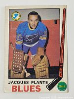 Front of 1969-70 OPC Jacques Plante hockey card in blue St. Louis Blues uniform with goalie equipment.