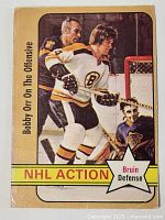 Front of the Bobby Orr hockey card showing player in Boston Bruins uniform, in action on ice near goal, with NHL action and Bruin Defense text.