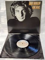Open view showing black vinyl LP record from album 'One Voice' by Barry Manilow. Label in center visible with track details.