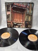 Two black vinyl LP records with orange CBS labels, accompanying the Julio Iglesias En el Olympia album.