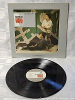 Vinyl record and original cover laid flat showing black vinyl disc with white label featuring Tears For Fears logo.