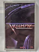 Front of cassette tape case showing dark purple cover with Triumph logo and "Classics" text.