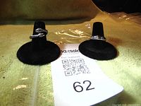 Two silver rings displayed on black ring holders, one with CZ stones and the other in a twisted rope design