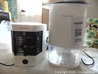 Photo showing the Arctic Air personal evaporative cooler alongside the Maxsold branded personal dehumidifier on a table.