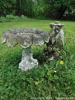 Bird bath and dolphin fountain in garden setting, showing weathering and moss