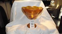 Side view of amber iridescent carnival glass fruit bowl on a pedestal stand.