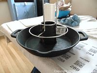 Full view of black cast iron chicken cooker with insert and handles for oven or BBQ use.