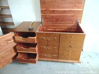 Cedar chest with top lid open revealing cedar-lined storage compartment on right, and three drawers open on the left side showing interior.