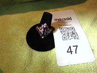 Front view of the sterling silver enamel ring displayed on a black stand, showing red enamel and blue gemstones.