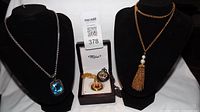 Blue gemstone pendant necklace, gold tassel pearl necklace, two Milo pocket watches on black display stands (stands not included in sale)