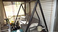Full view of the outdoor garden swing with cushioned seating and metal frame on porch.