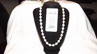 Pearl necklace displayed on black necklace form, showing full length and pearl spacing.