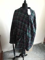 Full view of plaid cape displayed on a dress form showing tie belt and pattern detail