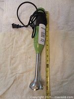 Full length view of green KitchenAid immersion blender with attached power cord and measuring tape, showing approximate length.