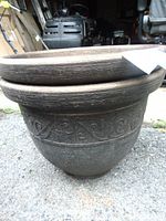 Close-up side view of one large plastic planter showing crackled texture and embossed vine scroll pattern.