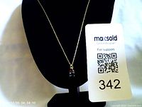 Photo of a gold-tone twisted chain necklace with a two-stone pendant (red and blue) displayed on a black necklace stand, accompanied by a MaxSold tag.
