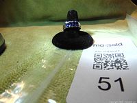 Ring displayed on black velvet cone with visible purple CZ stones and marked 925 sterling silver band.