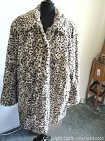 Front view of one of the faux fur cat print coats on a mannequin. Light beige background with black and dark brown cat-like pattern.