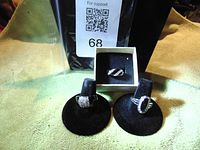 Three fashion rings displayed on black velvet holders and a white box behind them on a green surface.