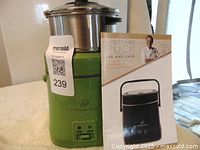 Green Wolfgang Puck mini cooker with stainless steel pot installed, use and care manual displayed next to it