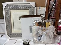 Lot showing two wedding frames, a large wood silver frame, a silver 8x10 frame, and a dove figurine decoration with lace fabric around it.