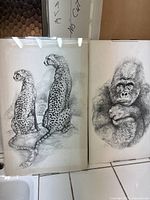 Photo of two pencil drawings: left is two cheetahs sitting on a rock, right is a gorilla portrait.