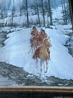 Close-up of two Indigenous riders on horseback traversing a snowy landscape with trees in background.