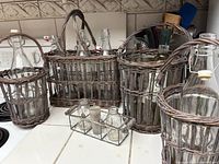 Wicker holders collection arranged on kitchen counter, showing multiple bottles in various basket styles