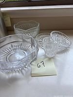 The cut crystal set arranged on a surface including a small pitcher, footed bowl, 6.5-inch bowl, and two coasters.