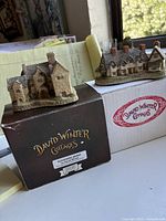 Two David Winter cottages displayed on original boxes: Blackfriars Granary on brown box, Craftsman Cottage on white box with red logo.
