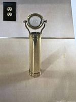 Front view of the vintage brass kaleidoscope and teleidoscope showing cylindrical body with flipping magnifying glass.