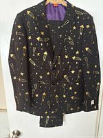 Full view of the black men's suit jacket and matching pants with gold rockets, stars, and champagne glass pattern.