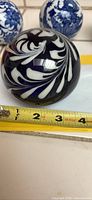 Photo showing the blue and white swirled glass paperweight with a measuring tape indicating approximately 4 inches in diameter.