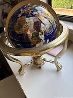 Photo of lapis gemstone globe showing Africa, Europe, and Asia with brass stand and compass visible below.
